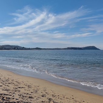 Calm Waves at Terrigal Beach, Terrigal, with whitewash waves reflecting the blue sky across yellow sand and a headland covering the horizon