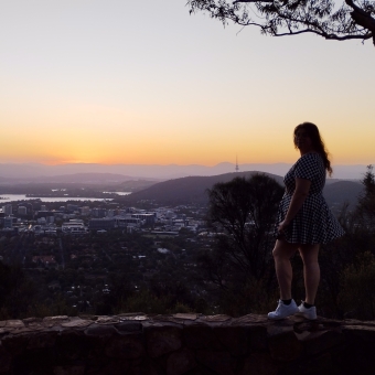 Mt Ainslie Lookout, Ainslie, with orange and magenta sunset across Canberra CBD and Telstra Tower in the distance, with someone
