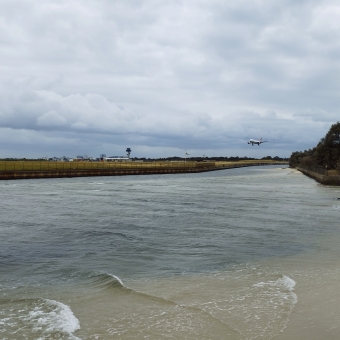 Mill Stream Lookout, Botany, with an aeroplane making its landing from right to left, with the runway and closer river going from the distance in the right to close left