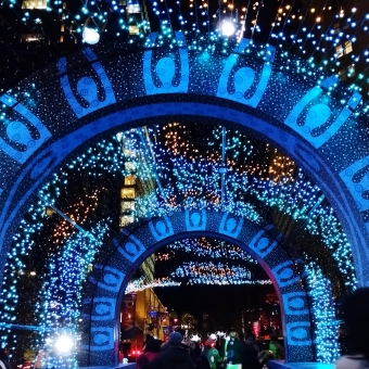 An Archway of Dreaming, Martin Place, with about a dozen blue simplified silhouettes in an arch shape which are reaching up to many blue dots strung like a blanket over their head