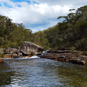 Kangaroo Creek Falls, Engadine Track, with rippling water across low rock-faces in the centre which comes towards, with trees then clouds then blue sky going back