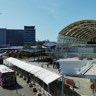 International City Purview, Sydney Airport International Terminal, with a hanger on the right and a multi-storey carpark on the left, with a small view of Sydney CBD in the centre