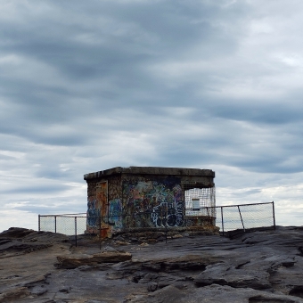 Rocky Outpost, Boora Point, with a grey derelict outpost on top of a grey rock shelf, with light grey clouds rolling over the top