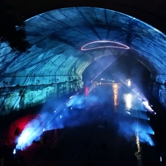 Everchanging Overpass, Argyle Cut, with the underside of the bridge covered in blue projections, with a laser-light making a circle in the middle of the underpass