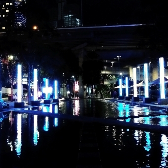 Azure Pillars, Darling Harbour, with brightly glowing almost-white blue pillars of tiny LED-lights lining a reflecting pool which they are reflected in